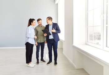Portrait of mature confident man professional realtor standing with couple clients in modern new...