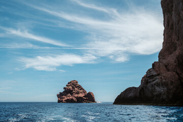 A tourist boat passes between the jagged rocks of the Scandola Nature Reserve created in 1975 on the west coast of the Mediterranean island of Corsica