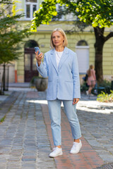 Caucasian mature businesswoman in formal suit using mobile GPS to find a direction. Middle-aged...