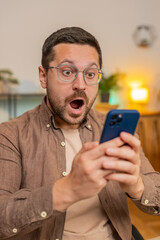 Oh my God, Wow. Caucasian young businessman using smartphone shocked by sudden victory game...