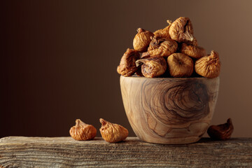 Organic dried figs in a wooden dish on a brown background.