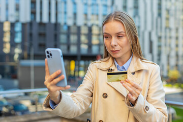 Caucasian mature businesswoman using credit card and smartphone while transferring money purchases...