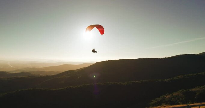 Paraglider gracefully glides through the air during sunset