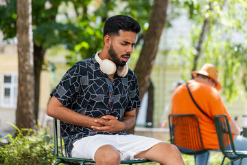 Indian man feeling sudden strong abdominal stomach liver kidney ache gastritis problem outdoors....