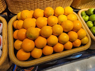 Vibrant oranges arranged in a woven basket on display. Great for use in healthy eating, supermarket...