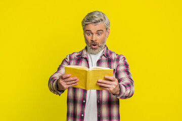 Mature man opens book with eager hope, showing bright surprise and stunned excitement. Middle-aged...