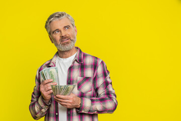 Mature man carefully counts dollar money cash bills, reflecting visible satisfaction joy over...