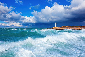 Stunning view of lighthouse standing tall against backdrop of stormy clouds and turbulent waves, evoking sense of nature power