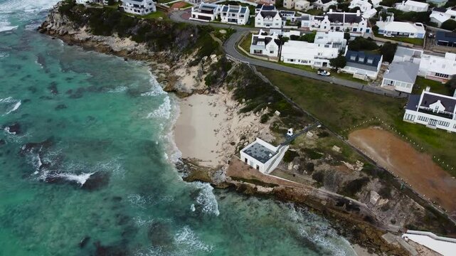 Camera panning up along the coastline and the town of Waenhuiskrans, Arnisto, an coastal town, 4K Aerial Video 