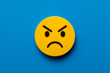 Fototapeta premium Round yellow painted circle with a sarcastic cartoon face on a bright blue background, symbolizing skeptical customer feedback or sarcastic team response for modern business communication visuals.