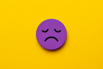 Fototapeta premium Tired cartoon face with an exhausted expression in purple on a soft pink background, ideal for illustrating workplace burnout, low employee morale, or business stress visuals for presentations.