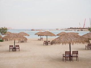 A serene Doha tranquil beach with straw umbrellas.