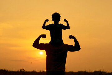 Silhouette of joyful father and son flexing their muscles against a stunning sunset backdrop outdoors