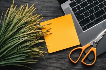 Creative workspace with scissors and sticky note beside a laptop and decorative plant