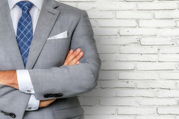Man in Patterned Suit Posing in Front of White Brick Wall With Arms Crossed