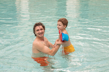 happy dad and son in the pool in summer