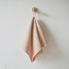 Peach waffle towel hanging on hanger on light gray wall. Kitchen towel mockup. Blank cloth napkin template. Empty dish towel template. Natural tea towel in minimalist style