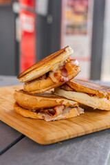 Zoom sur des burgers empilés et disposés sur une planche en bois. Burgers réalisés par un restaurateur spécialisés.