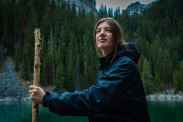 Woman sitting and holding a stick near lake