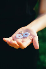 Hand Holding Blue Flower-Shaped Earrings in Sunlight