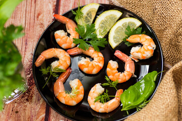 Close-up of boiled shrimps with lemon slices, on a wooden table