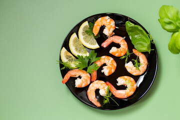 Ready to eat red shrimps with lemon isolated on green background