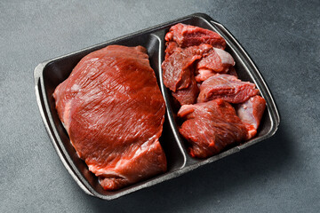 Fresh meat. Raw piece of beef. Meat on a plastic black container from the market. Close-up.