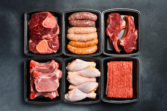 Different types of raw fresh meat and steaks in plastic boxes. Products from the market. Top view.