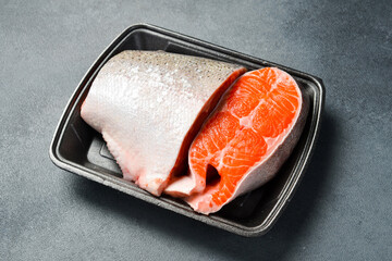 Fresh fish. Juicy piece of raw salmon or trout fish. Fish on a plastic black container from the...