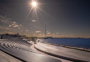 A modern amphitheater on the shore of the bay illuminated by the sun.