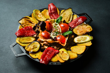 Saj - traditional Azerbaijani food. Lamb saj in a metal pan. Free space for text. On a dark background.