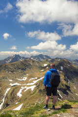 Fototapeta premium A man hiking through the mountains embraces adventure, surrounded by rugged trails, fresh air, and breathtaking views.