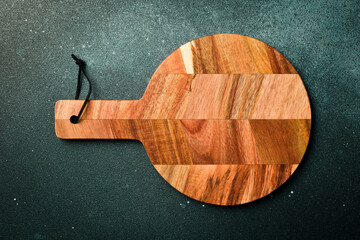 Kitchen wooden cutting board on a dark stone background. Top view. Free space for text.