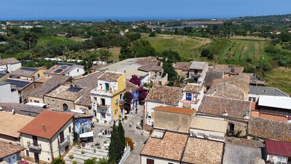 Obraz premium Borgo Parrini, Palermo, Sicilia, Italia - 06/15/2025: Case dipinte dell'antico Borgo detto anche la Barcellona di Partinico. Ripresa aerea con drone di Borgo Parrini, meta turistica della Sicilia.