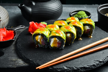 Sushi with black rice, fish and avocado on a rustic dark background. Sushi rolls, nigiri, maki, pickled ginger, wasabi, soy sauce. Sushi set on a table.
