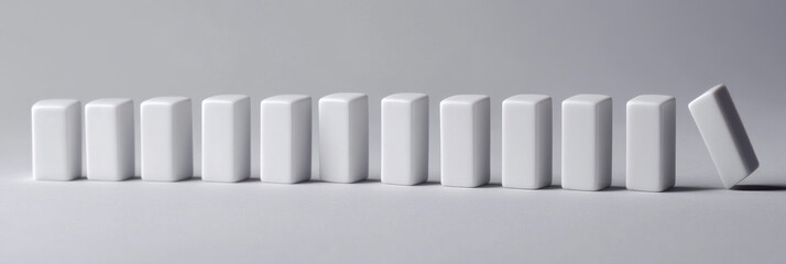 One domino falls, starting a chain reaction affecting many others. This symbolizes risk, influence, and interconnectedness.