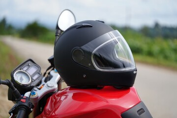 A black motorcycle helmet rests on a vibrant red bike fuel tank