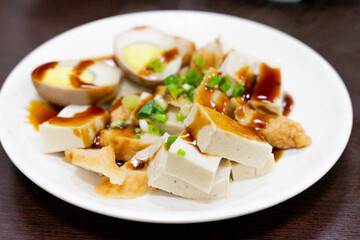A plate of traditional Taiwanese braised snacks featuring soy-marinated egg, dried tofu, and tofu skin slices. Rich in color and flavor, this savory dish is a staple side at many local eateries