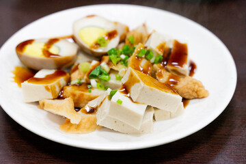 A plate of traditional Taiwanese braised snacks featuring soy-marinated egg, dried tofu, and tofu skin slices. Rich in color and flavor, this savory dish is a staple side at many local eateries