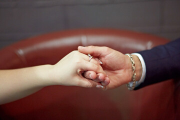 A couple is holding hands and the woman is wearing a ring