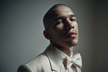 portrait of person in light suit emphasizing bright bow tie against clean background