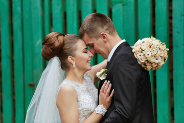 The bride is wearing a white dress and the groom is wearing a black suit