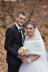 A bride and groom are posing for a picture in a forest