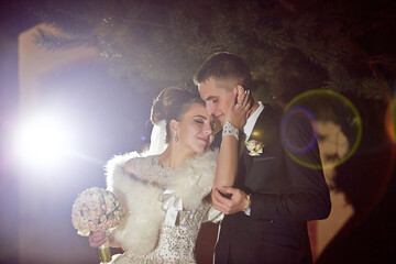 A bride and groom are embracing each other in a dimly lit room