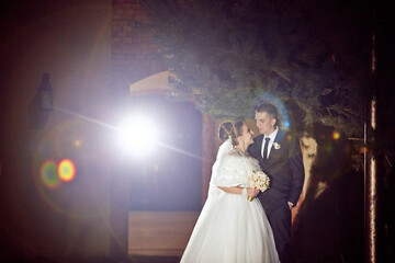 A bride and groom are standing together in the dark