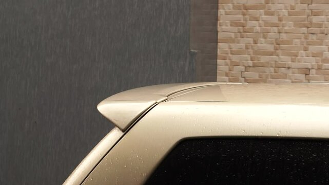Rain water drops on old gold car back exterior with spoiler, video of rainy day. winter season.	
