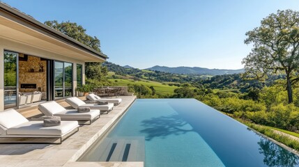 Fototapeta premium A view of the hills from an infinity pool with la white lounge chairs, overlooking distant mountains