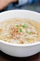A comforting bowl of Taiwanese minced pork noodles served in a light savory broth. Tender noodles soak up the flavorful soup, topped with green onions and soy-braised pork, making it a perfect rainy d