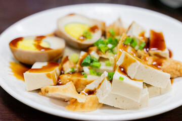 A plate of traditional Taiwanese braised snacks featuring soy-marinated egg, dried tofu, and tofu skin slices. Rich in color and flavor, this savory dish is a staple side at many local eateries