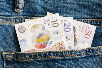 British pound banknotes in denim pocket. Ten twenty fifty pound notes visible in jeans. Concept of...